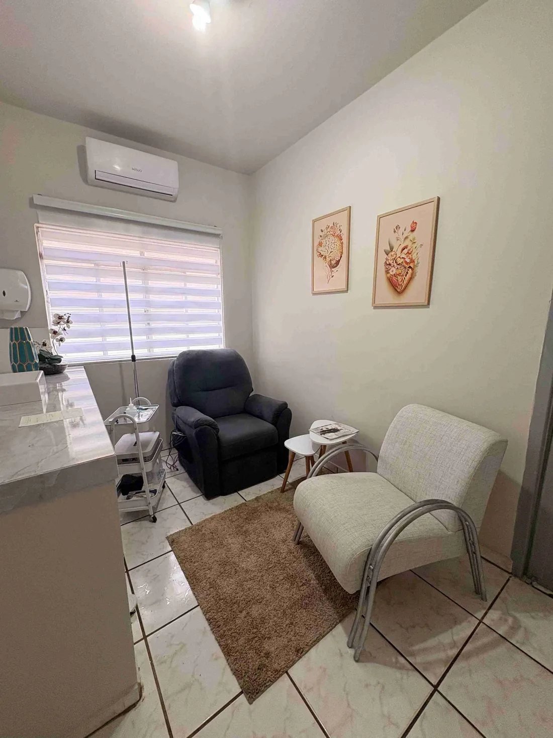 Sala de atendimento, com poltrona reclinável, suporte de soro e carrinho de materiais